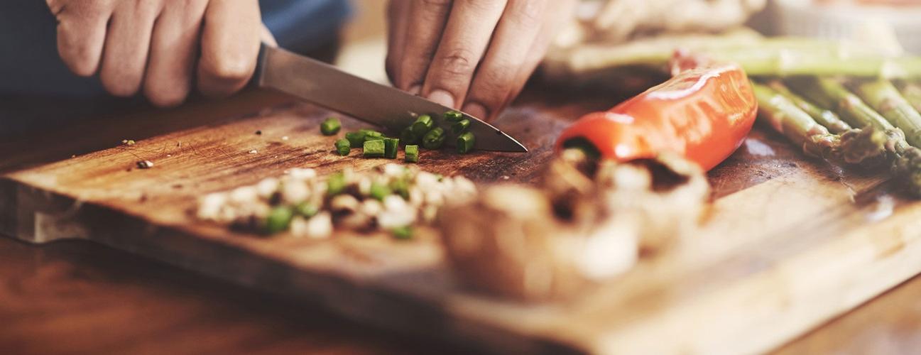 a closeup of a man's hands chopping vegetables