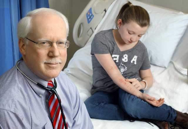 Dr. 罗伯特·伍德和他的儿科过敏bet8九州下载在医院病房里，她看着自己手臂上的过敏测试结果